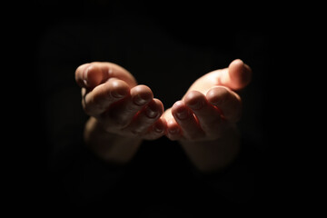 Religion. Woman with open palms praying on black background, closeup