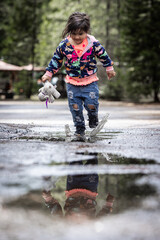 A young girl is playing in the rain, splashing water