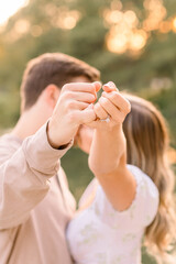 A sunset kiss with an engaged couple with their fingers making a pinkie promise showing off her engagement ring. 