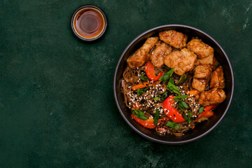 Fried Udon with Chicken and vegetables on dark green background. Top view. Asian food.