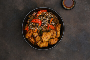 Fried Udon with Chicken and vegetables on dark brown background. Top view. Asian food.