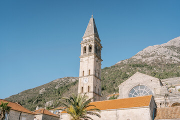 Bell tower of the Church of St. Nicholas against the backdrop of the mountains. Perast, Montenegro