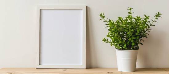 White empty frame and potted plant on a wooden table. Mockup.