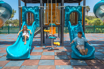 Schoolchild playing in a playground together sliding a slide