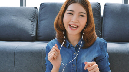 Happy asian smiling woman use earphones dancing listen to music smartphone dance in living room at cozy home. Music mental therapist relaxation woman happiness. Cheerful women dance exercise at home - Powered by Adobe