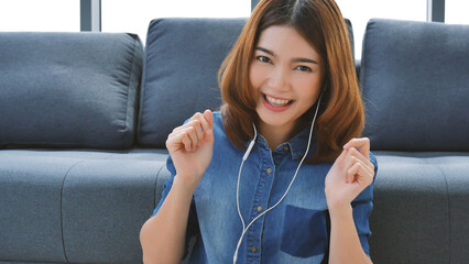 Happy asian smiling woman use earphones dancing listen to music smartphone dance in living room at cozy home. Music mental therapist relaxation woman happiness. Cheerful women dance exercise at home