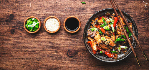 Stir fry turkey slices with red paprika, mushrooms, chives and sesame seeds with ginger, garlic and soy sauce. Old wooden table background, top view banner
