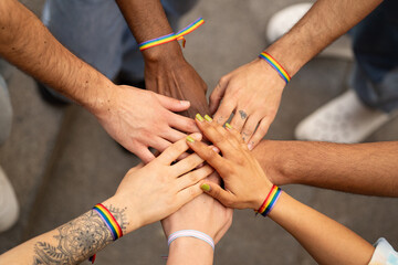 LGBTQ embrace and greet each other at the parade. Close up hands with rainbow bracelets.Concept of unity and inclusivity - obrazy, fototapety, plakaty