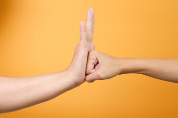 Hand with open palm stopping angry punch over yellow background. Fist and palm.