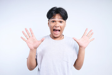 Young Asian man with short hair raising his both palms showing shocked surprise expression