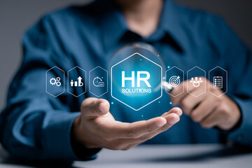HR Solutions concept. Businessman holding human resources solutions icons on virtual screen for human resources management tool used to manage employee information in organization.