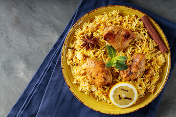 Plate of Chicken Biryani with Spices, Fresh Mint and Lemon on Dark Background, Copy Space