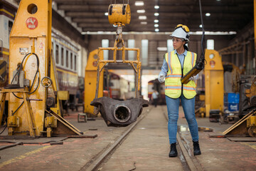 Portrait of railway technician worker in safety vest and helmet working at train repair station