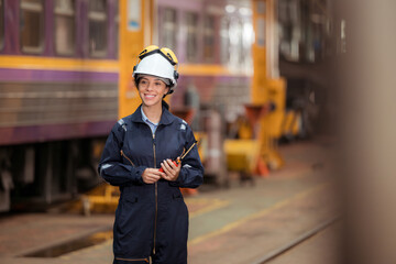Portrait of railway technician worker in safety vest and helmet working and using a walkie talkie...