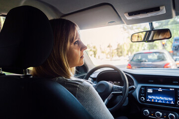 Woman in a car looking thoughtfully. Interior view.