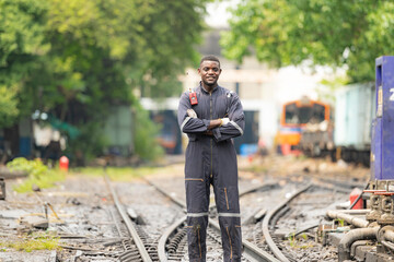 Portrait of a railway engineer standing on the tracks of a train in station platform.
