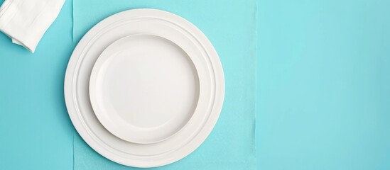 White plate and cotton napkin placed on a blue background. Ideal setting for a food-themed menu or recipe book, featuring a top-down view. - obrazy, fototapety, plakaty