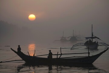 Indonesian fishermen on a misty morning, their boats silhouetted against the rising sun as they head out to sea, Generative AI
