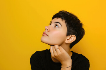 Portrait of a woman with a short hairdo, looking up in deep thought, isolated on a yellow background