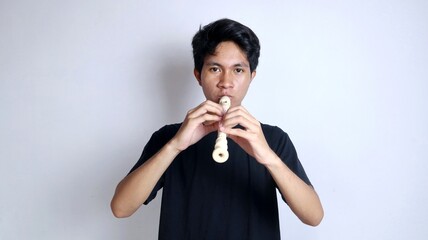 Young Asian man happy and active gesturing playing the flute