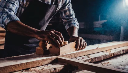 Photo sur Plexiglas Ancien avion Carpenter's hands planing a plank of wood with a hand plane, in factory, old, dark 