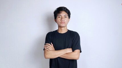 Obraz premium Handsome young Asian man gesturing with crossed arms and wearing a black shirt