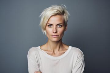 Portrait of a beautiful blonde woman with short hair on a gray background - obrazy, fototapety, plakaty