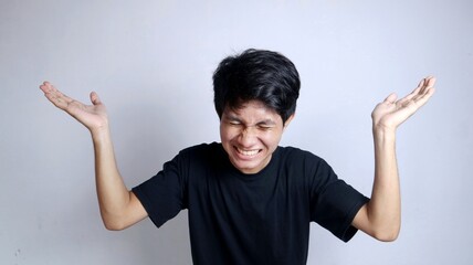 Young Asian man enthusiastically gesturing with both open palms raised upwards