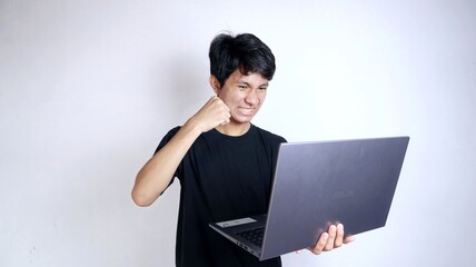 young asian man angry with gesture holding laptop with isolated white background