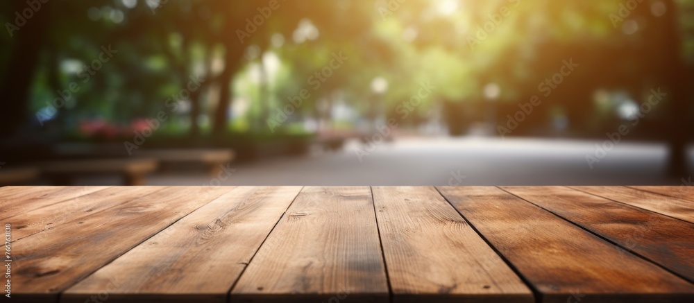 Poster a wooden table sits empty against a backdrop of trees in a park, blending in with the natural surrou