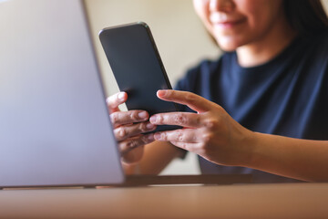 Closeup image of a young woman using smart phone and laptop computer