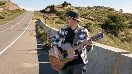 Artista, músico y cantante tocando la guitarra en la carretera. 
