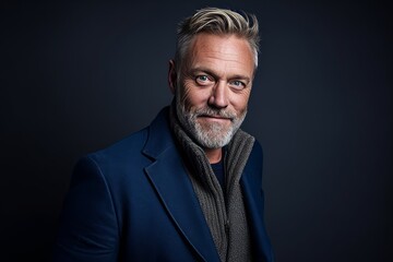 Portrait of a senior man with grey hair and beard wearing a blue coat.