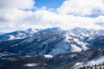 A view of snowy mountains and puffy clouds on a sunny winter day in Mammoth Lakes, CA