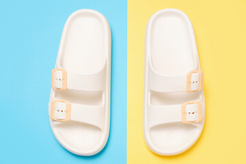 Rubber summer flip-flops on blue and yellow background close-up.