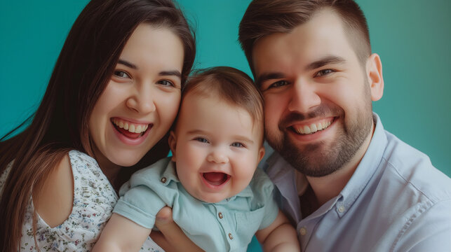 Beautiful young parents and their cute little son have fun on teal color background professional photography
