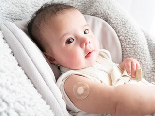 Band-aid on baby's right arm after vaccination