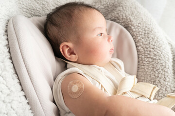 Band-aid on baby's right arm after vaccination