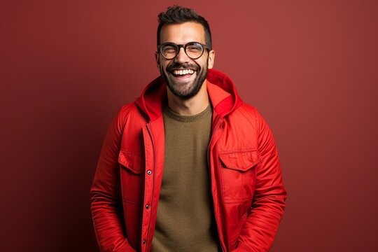 Handsome man wearing a red jacket and glasses on a burgundy background