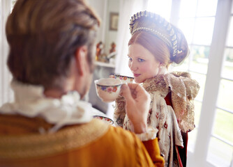 Man, woman and royal costume for tea party with conversation, vintage clothes and style in castle. King, queen and couple with drink together in morning with Victorian fashion at regal palace in UK - obrazy, fototapety, plakaty
