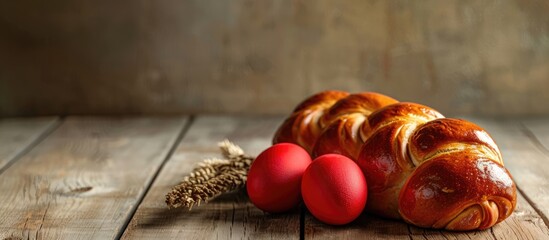 Traditional Easter bread called Greek tsoureki and red eggs displayed on a wooden table in a closeup view with space for text.
