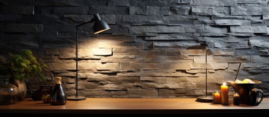 There is a lamp positioned on a table placed next to a textured stone wall
