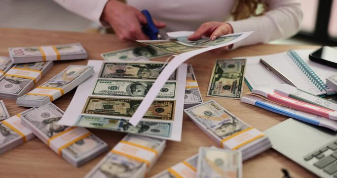 Woman forger cuts fake printed money with scissors at table