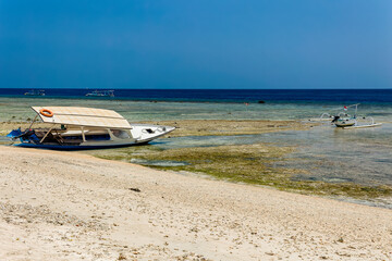 Old and new wooden boats in shallow water off the beach of a small tropical island