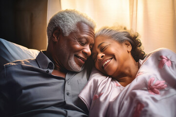 An elderly dark-skinned man and woman sitting side by side on a bed, showing love and affection towards each other