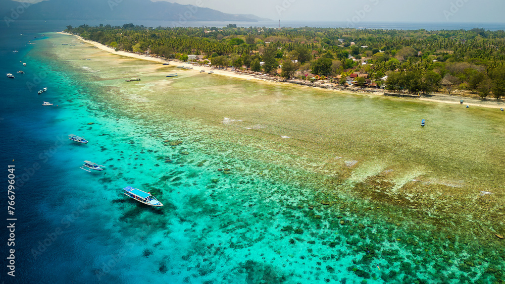 Sticker Tourist boats moored on the edge of a fringing coral reef off the coast of a tropical island at low tide