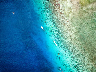 Top down aerial view of snorkel boats and tourists over a tropical coral reef in a warm ocean