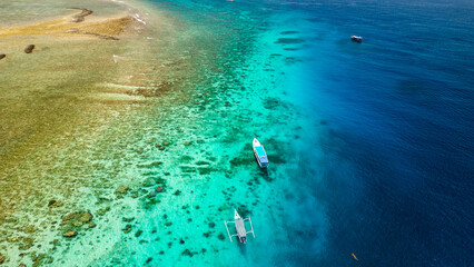 Aerial view of swimmers and snorkellers from tourist boats above a tropical coral reef in a warm...