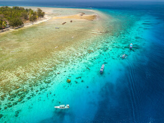 Aerial view of swimmers and snorkellers from tourist boats above a tropical coral reef in a warm ocean (Gili Air, Indonesia)