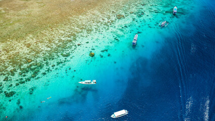 Aerial view of swimmers and snorkellers from tourist boats above a tropical coral reef in a warm ocean (Gili Air, Indonesia)